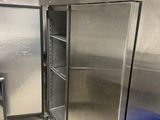 des réfrigérateurs en acier inoxydable dans une cuisine professionnelle, avec une poubelle bleue