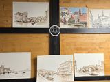 quatre tableaux accrochés au mur d'une pièce où se trouve une horloge murale