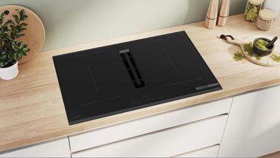 une photo d'une plaque de cuisson noire posée sur un plan de travail en bois