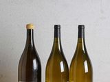 trois bouteilles de vin posées sur une table en bois à côté d'une bouteille de vin