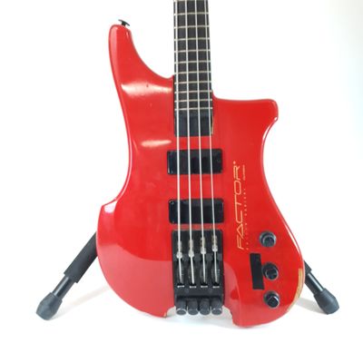 a red electric bass guitar on a stand on a white surface