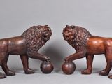 pair of carved wooden lions with ball on feet
