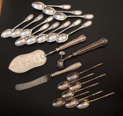 de nombreuses cuillères et couteaux-cuillères en argent posés sur une table