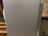 a silver dishwasher sitting on a pallet in a warehouse