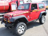 a red jeep parked in a parking lot next to a red truck