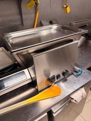 plan de travail en acier inoxydable dans une cuisine professionnelle, avec une spatule jaune posée dessus
