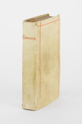 un vieux livre posé sur une table à côté d'un mur blanc