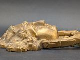 a gold statue of a person laying down on the ground