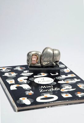un éléphant en argent posé sur un livre, lui-même posé sur une table