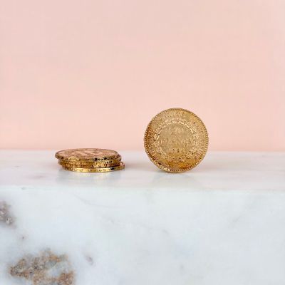 two gold coins sitting on top of a marble counter next to a pink wall