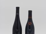 two bottles of wine sitting next to each other on a white surface