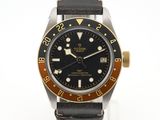 une montre noire et dorée montée sur un bracelet en cuir noir