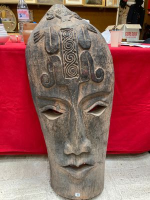 a wooden mask on a table with a red table cloth