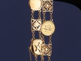 un gros plan sur la main d'une personne tenant un bracelet orné de pièces de monnaie