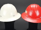 two hard hats are sitting side by side on a black surface