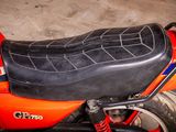 a red motorcycle with a black seat sitting in a garage