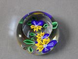 a glass paperweight with purple and yellow flowers on it