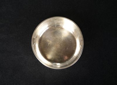silver plate on black cloth with a small hole in the middle of it