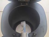 a black toilet with a metal lid on a table