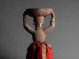 an old clay figurine of a woman holding a bowl on her head