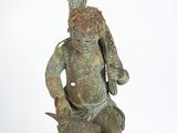 une statue représentant un homme assis sur un rocher, un bol sur la tête