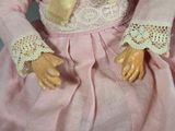 a close up of a doll wearing a pink dress