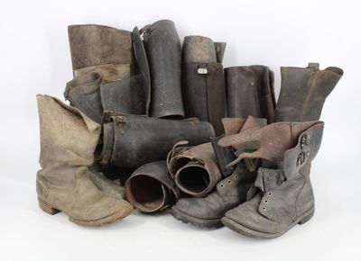 many pairs of old boots sitting on a white surface