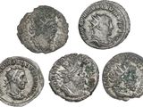 four ancient roman coins, one of which has a head of a man