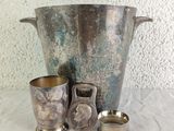 a silver vase and two silver cups on a table