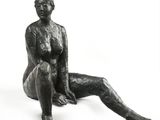 une statue représentant une femme assise sur une surface blanche