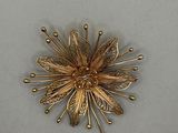 a gold flower brooch on a white surface