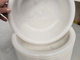 a person holding a stack of white plates on a table