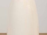 un vase blanc avec un couvercle noir posé sur une table