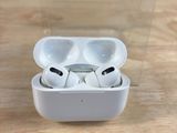 Des AirPods de la marque Apple sont posés dans une boîte transparente sur une table en bois