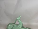 green ceramic sculpture of a woman laying on her back