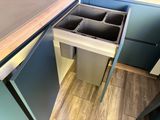 a kitchen with a sink and a trash can in it