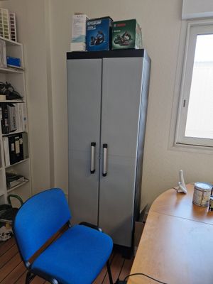 a blue chair sitting in front of a silver refrigerator