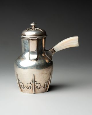 une théière ancienne en argent, dotée d'une poignée en bois sur un fond blanc