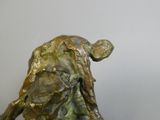 statue of a man sitting on a rock with his back to the camera