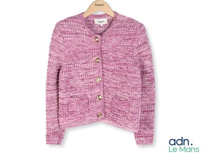 un cardigan rose sur un cintre, sur fond blanc