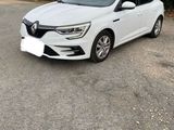 une voiture blanche garée sur un parking à côté d'une haie
