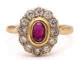 a close up of a gold ring with a ruby and diamond center