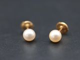 a pair of pearl stud earrings on a black surface