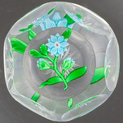 un cendrier en verre orné d'une fleur bleue