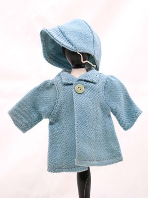 une poupée qui porte un manteau bleu et un chapeau