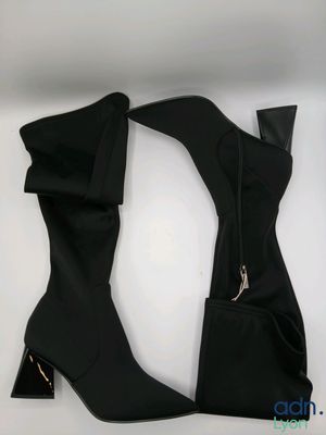 Ces bottes sont noires et comportent une fermeture éclair sur le côté.