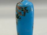 a blue vase with flowers on it sitting on a table