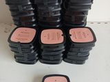 a pile of black and pink containers with pink labels on them
