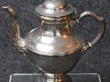 a silver tea pot sitting on a glass stand