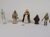 Plusieurs figurines de Star Wars sont alignées sur une surface blanche